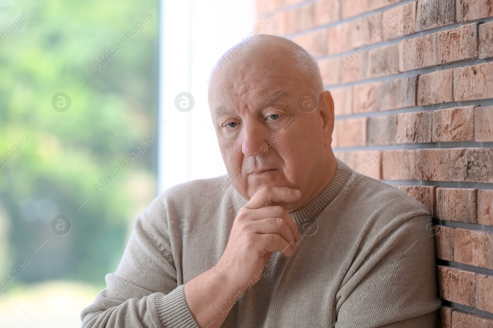 Photo of Senior man in state of depression near brick wall