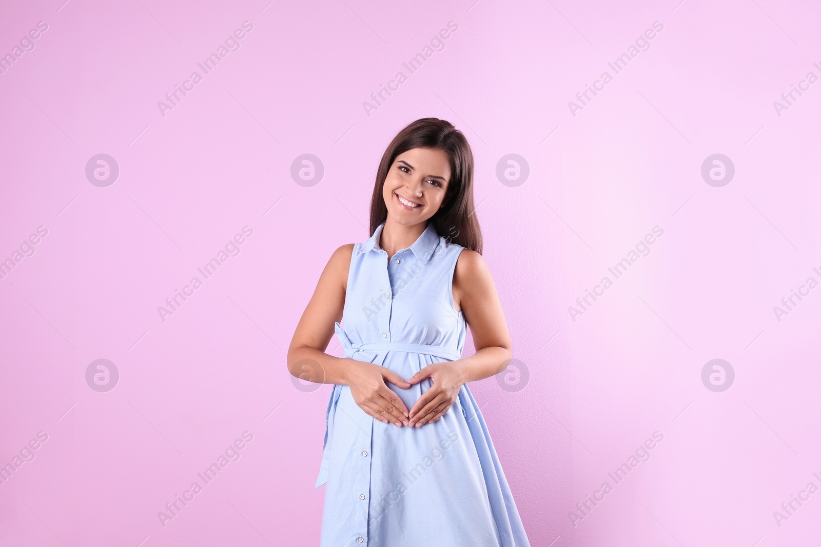 Photo of Happy pregnant woman posing on color background