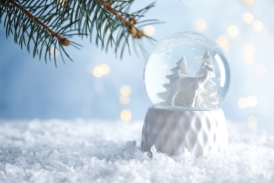Photo of Glass globe with deer and trees on artificial snow. Space for text