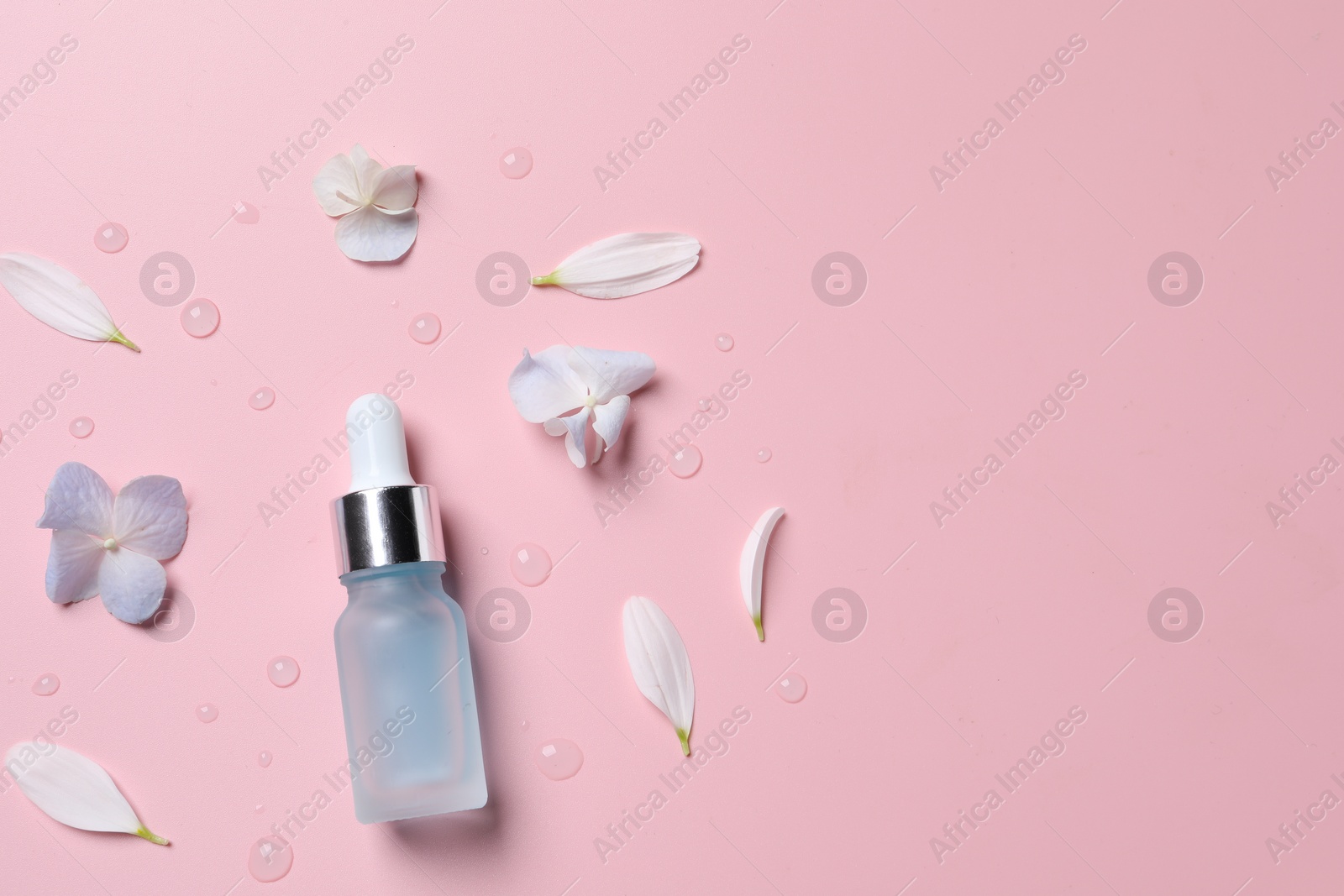 Photo of Bottle of cosmetic serum and beautiful flowers on pink background, flat lay. Space for text