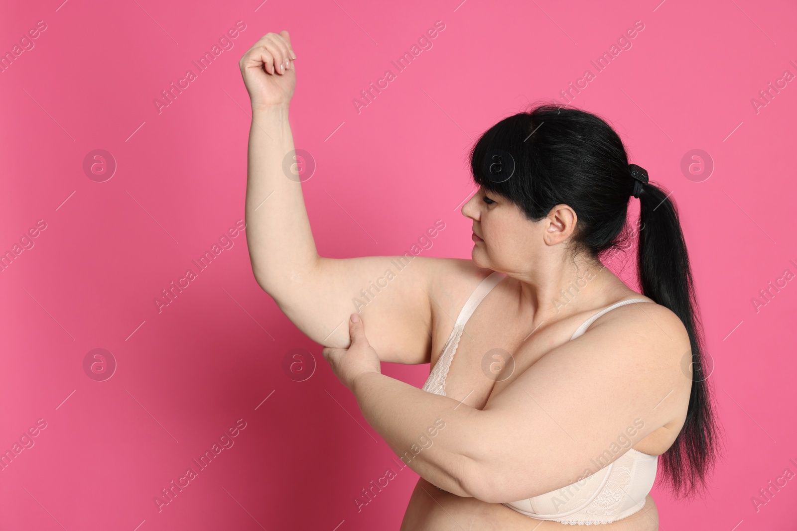 Photo of Obese woman with flabby arm on pink background, space for text. Weight loss surgery