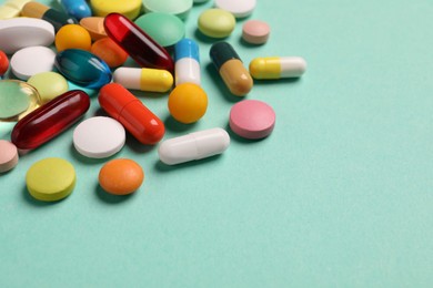 Photo of Many different pills on turquoise background, closeup. Space for text