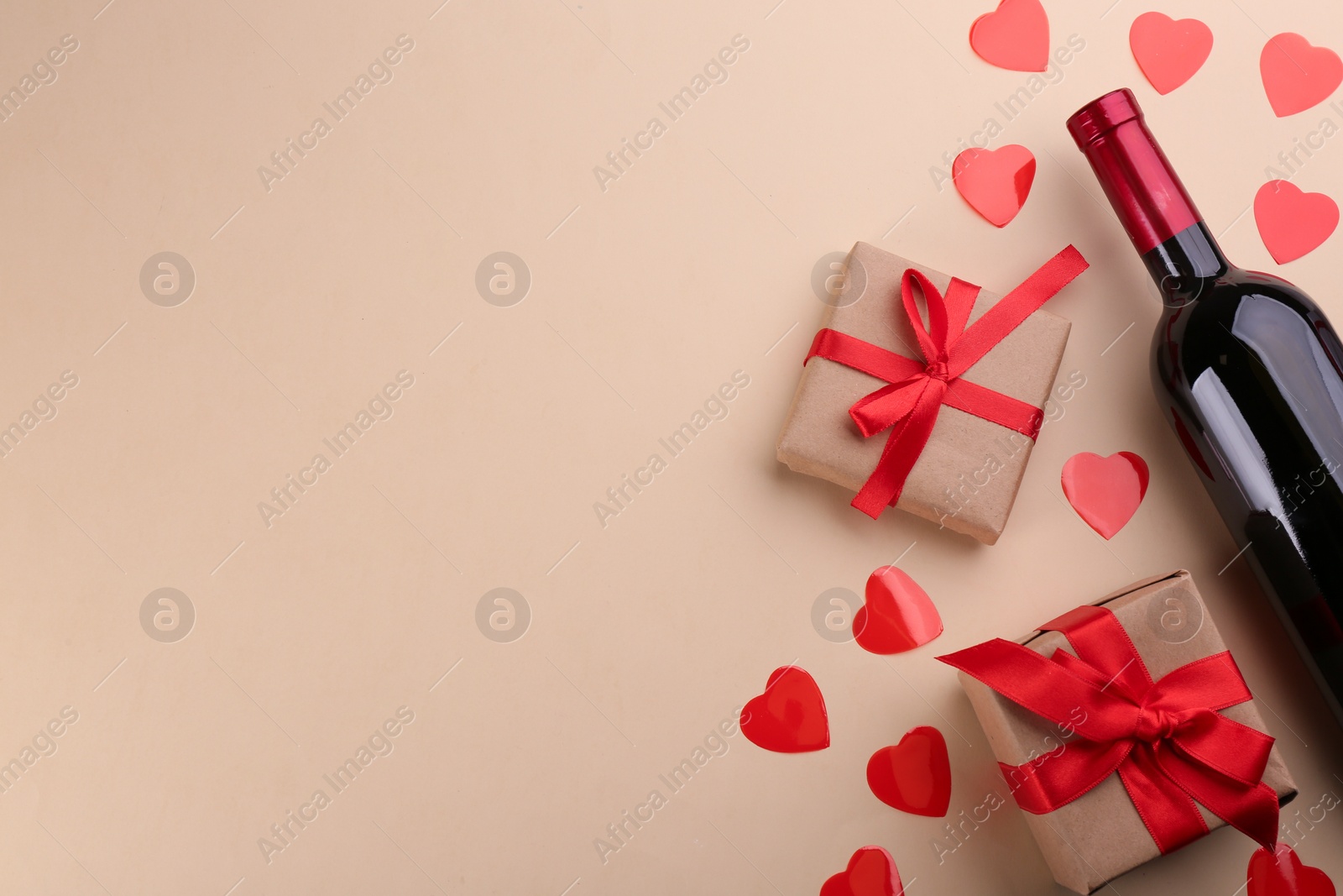 Photo of Beautiful gift box, hearts and wine on beige background, flat lay with space for text. Valentine's day celebration