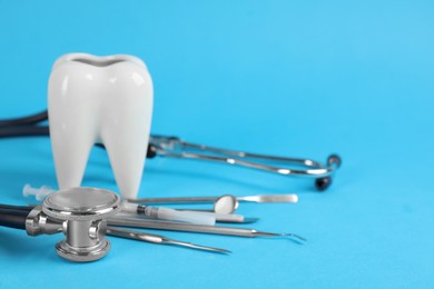 Photo of Tooth shaped holder, different dentist's tools and stethoscope on light blue background. Space for text
