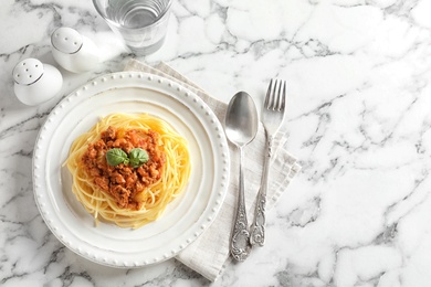 Plate with delicious pasta bolognese on marble background, top view