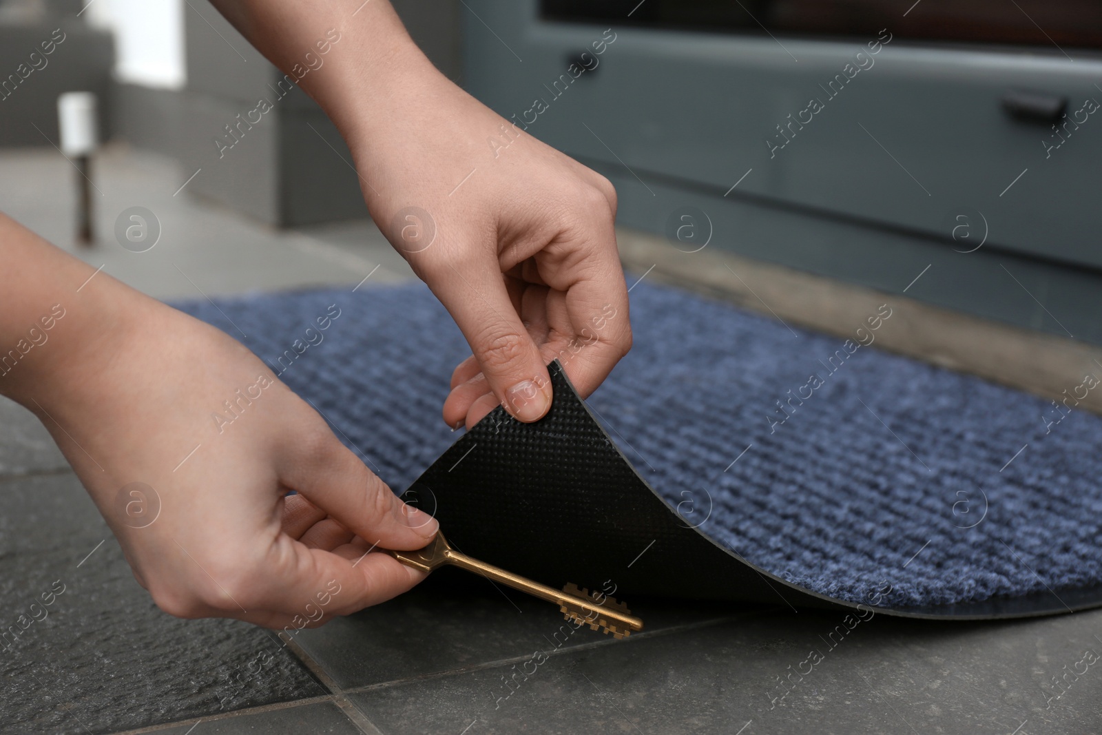 Photo of Woman hiding key under door mat, closeup. Space for text