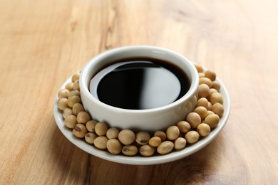 Dish of soy sauce with beans on wooden background