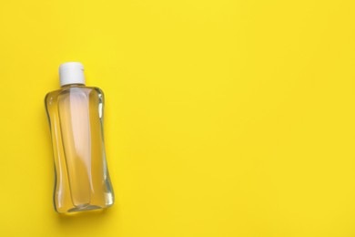 Photo of Bottle of baby oil on yellow background, top view. Space for text