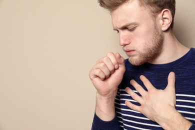 Photo of Handsome young man coughing against color background. Space for text