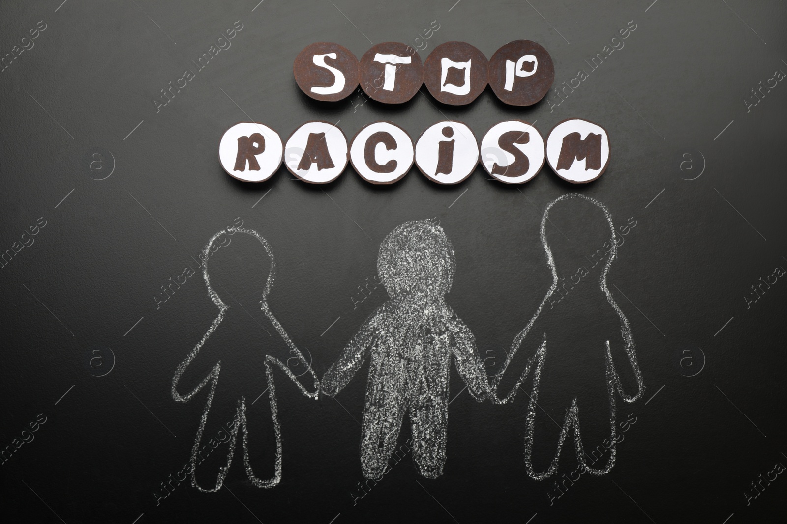 Photo of Phrase Stop Racism near white and black people drawn on blackboard, flat lay