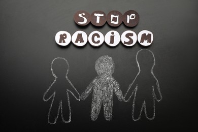 Photo of Phrase Stop Racism near white and black people drawn on blackboard, flat lay