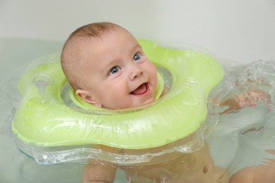 Photo of Cute little baby swimming with inflatable ring in bath