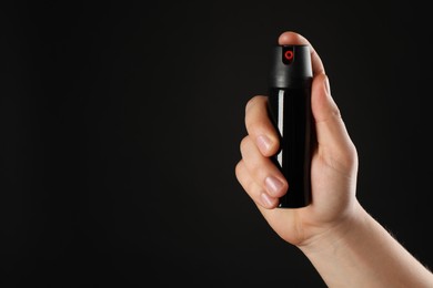 Photo of Man holding pepper spray on black background, closeup. Space for text