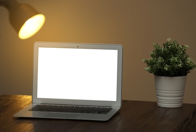 Photo of Laptop with blank screen on table indoors. Space for text