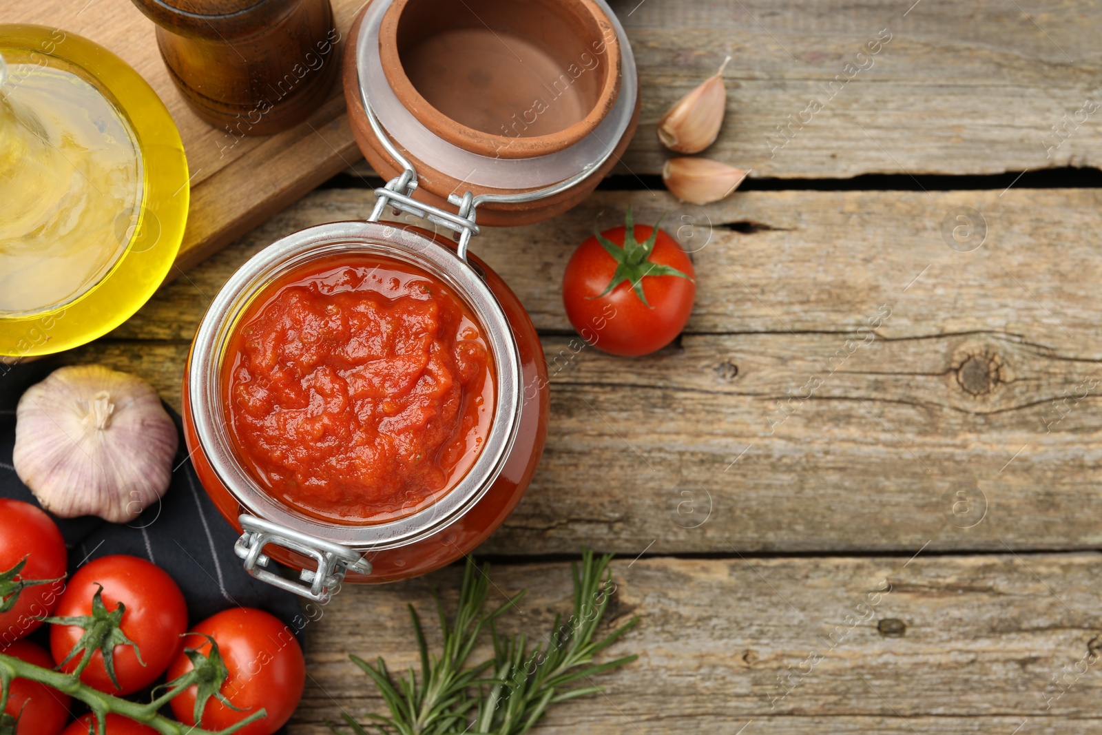 Photo of Homemade tomato sauce in jar and fresh ingredients on wooden table, flat lay. Space for text