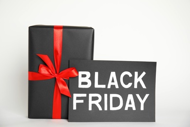 Photo of Gift box and sheet of paper with words Black Friday on white background
