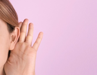 Young woman with hearing problem on color background, closeup. Space for text