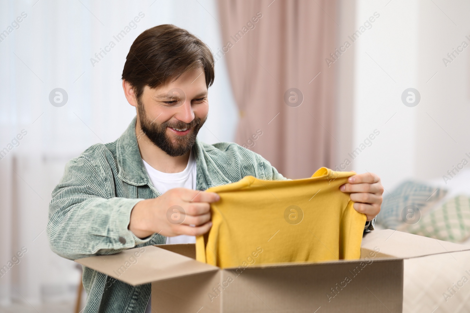 Photo of Happy man with parcel at home. Internet shopping