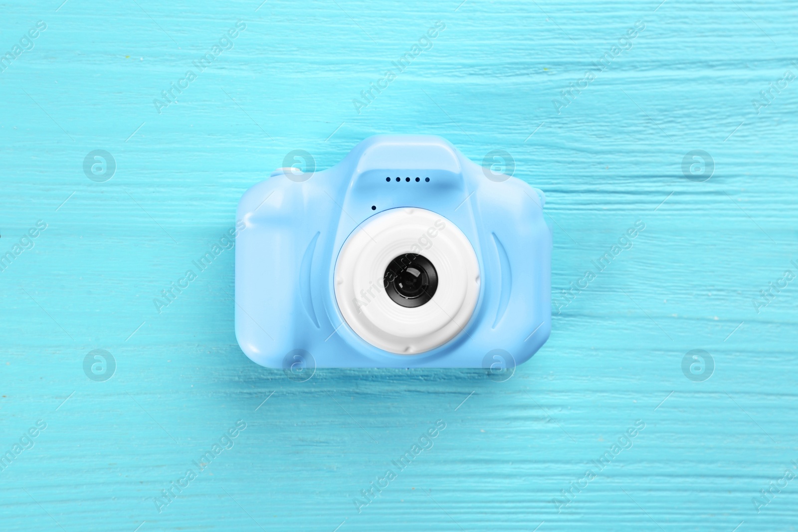 Photo of Toy camera on light blue wooden background, top view