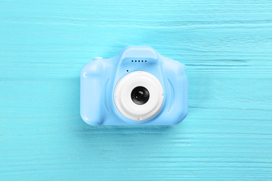 Toy camera on light blue wooden background, top view