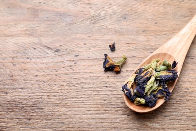 Photo of Spoon and dry organic blue Anchan on wooden table, flat lay with space for text. Herbal tea