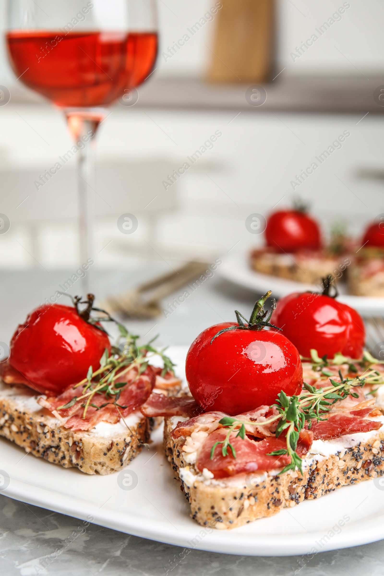 Photo of Plate of delicious bruschettas with prosciutto on grey kitchen table