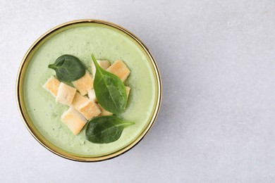 Delicious spinach cream soup with croutons in bowl on light grey table, top view. Space for text