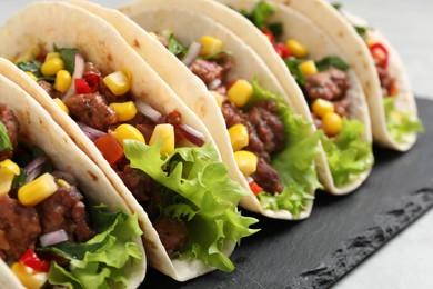 Photo of Delicious tacos with meat and vegetables on table, closeup