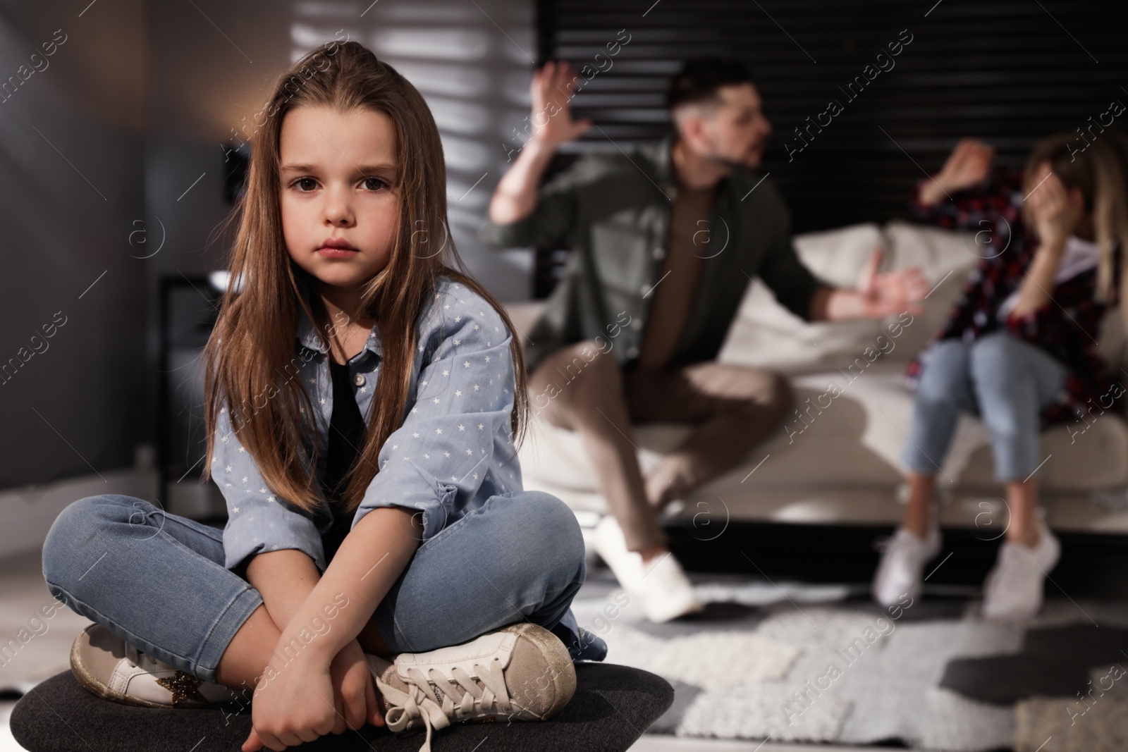 Photo of Couple fighting at home, focus on their unhappy little daughter. Domestic violence