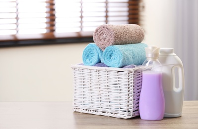 Photo of Basket with towels and detergents on table in room