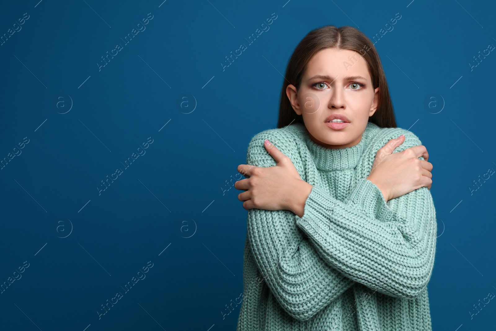 Image of Young woman suffering from fever on blue background, space for text. Cold symptoms