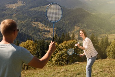 Couple playing badminton in mountains on sunny day