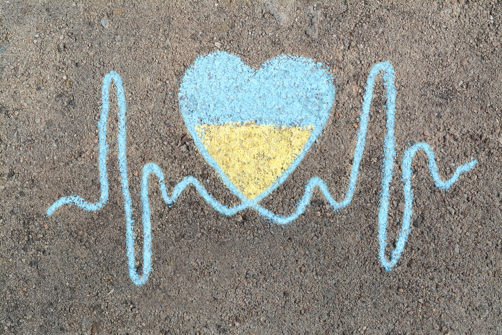 Photo of Cardiogram line with heart drawn by blue and yellow chalk on asphalt, top view