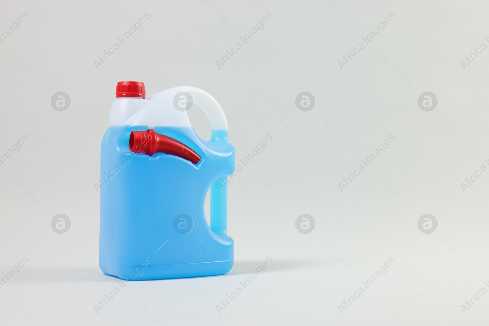 Photo of Plastic canister with nozzle and blue liquid on light grey background, space for text