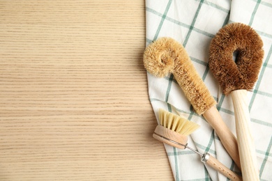Photo of Cleaning brushes on wooden table, flat lay and space for text. Dish washing supplies