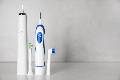 Photo of Electric toothbrushes and replacement brush heads on light background, space for text