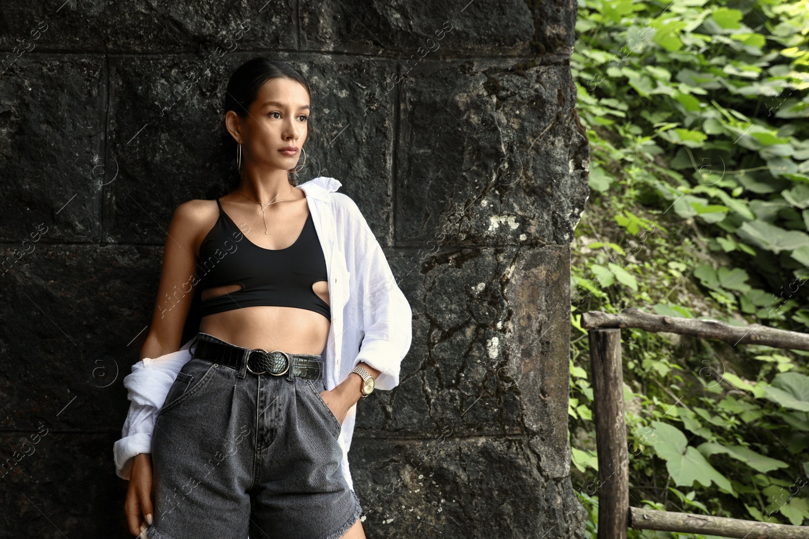 Photo of Beautiful young woman near stone wall outdoors, space for text