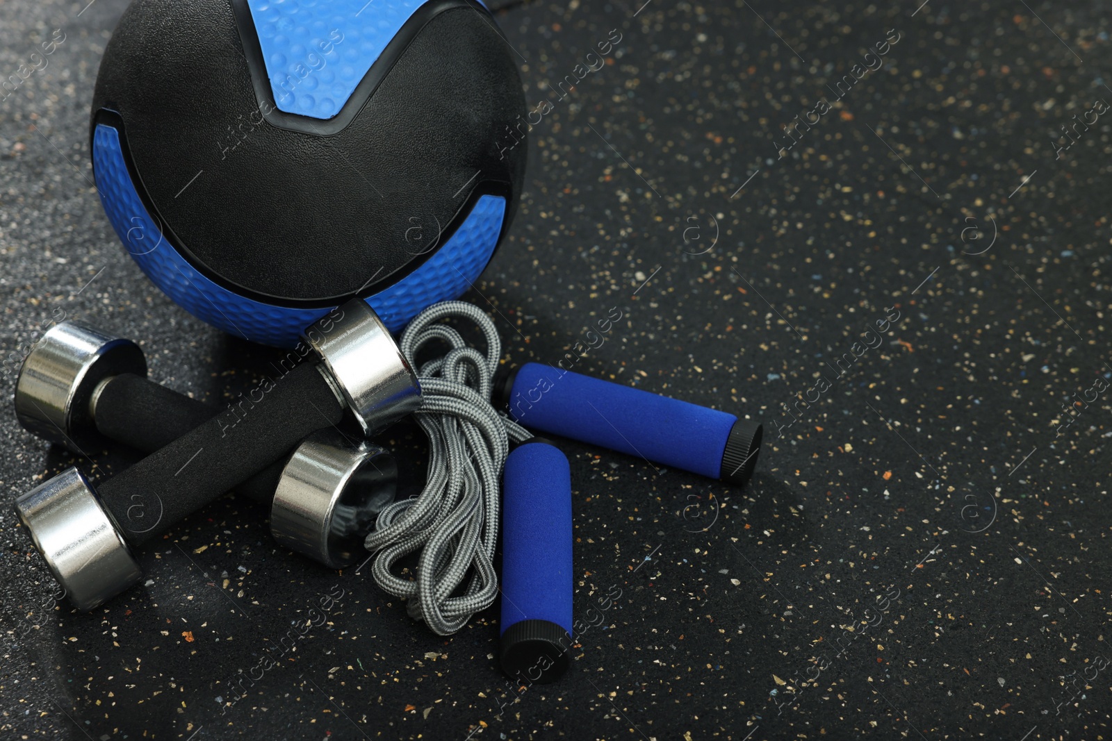 Photo of Blue medicine ball, dumbbells and skipping rope on floor, space for text