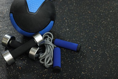 Photo of Blue medicine ball, dumbbells and skipping rope on floor, space for text