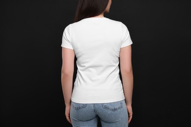 Photo of Woman wearing white t-shirt on black background, back view