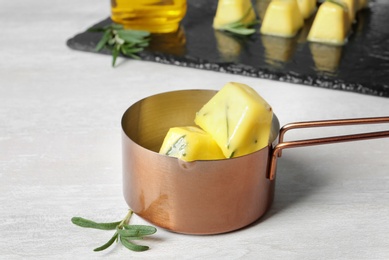 Photo of Rosemary and olive oil ice cubes in saucepan on light table