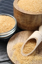 Photo of Brown sugar in bowls and scoop on table, closeup