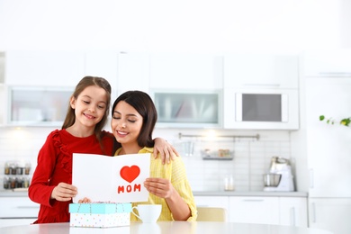 Photo of Daughter congratulating her mom in kitchen, space for text. Happy Mother's Day