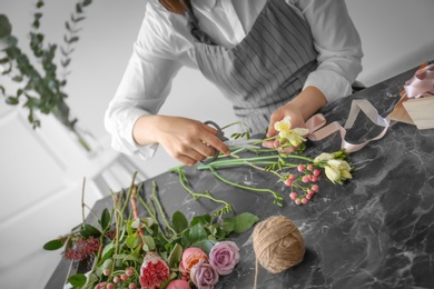 Photo of Female florist creating beautiful bouquet at table