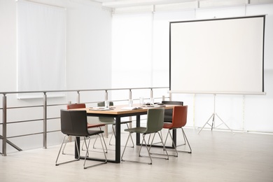 Photo of Modern meeting room interior with large table and projection screen