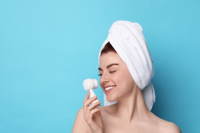 Photo of Washing face. Young woman with cleansing brush on light blue background, space for text