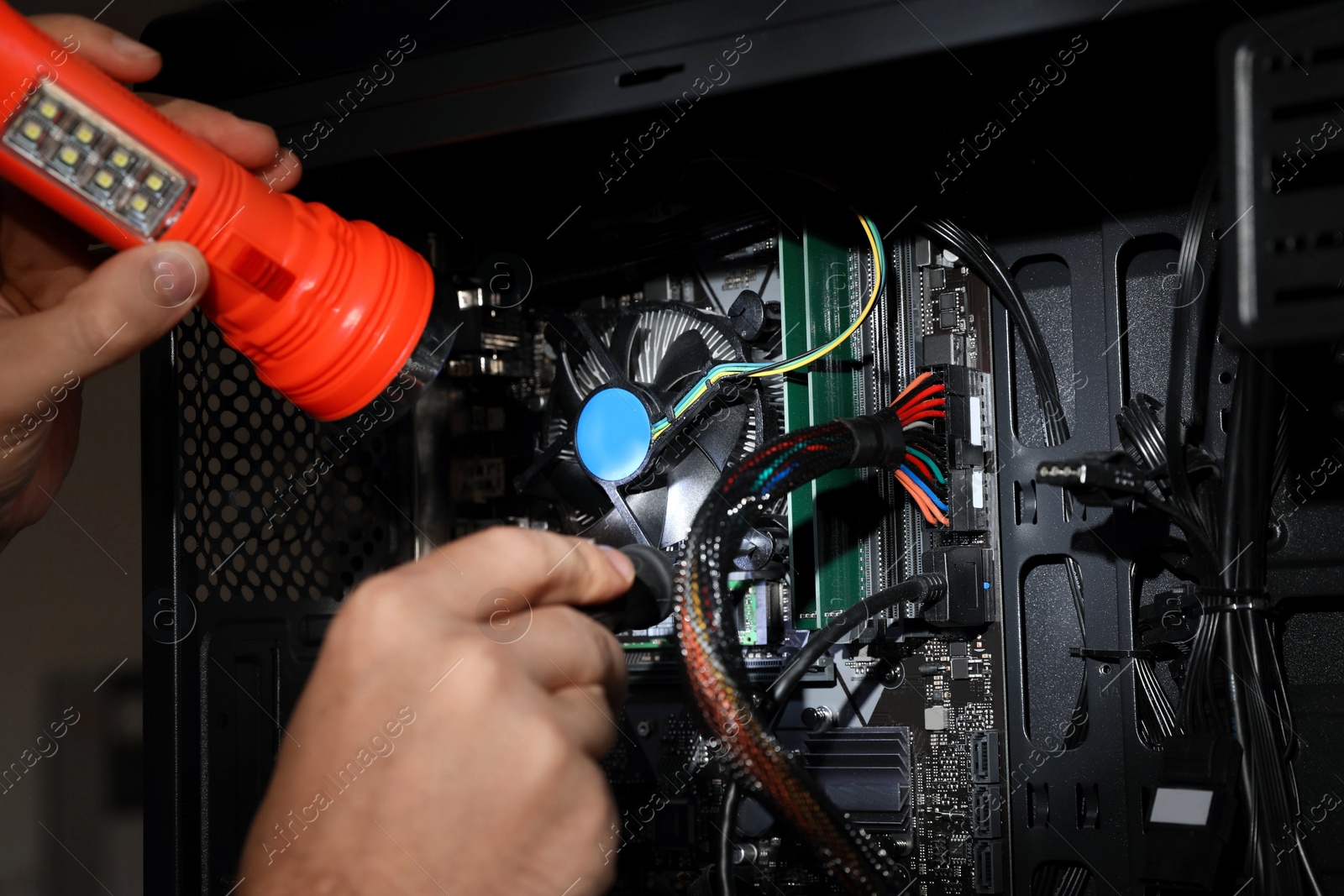 Photo of Man with flashlight fixing system unit indoors, closeup