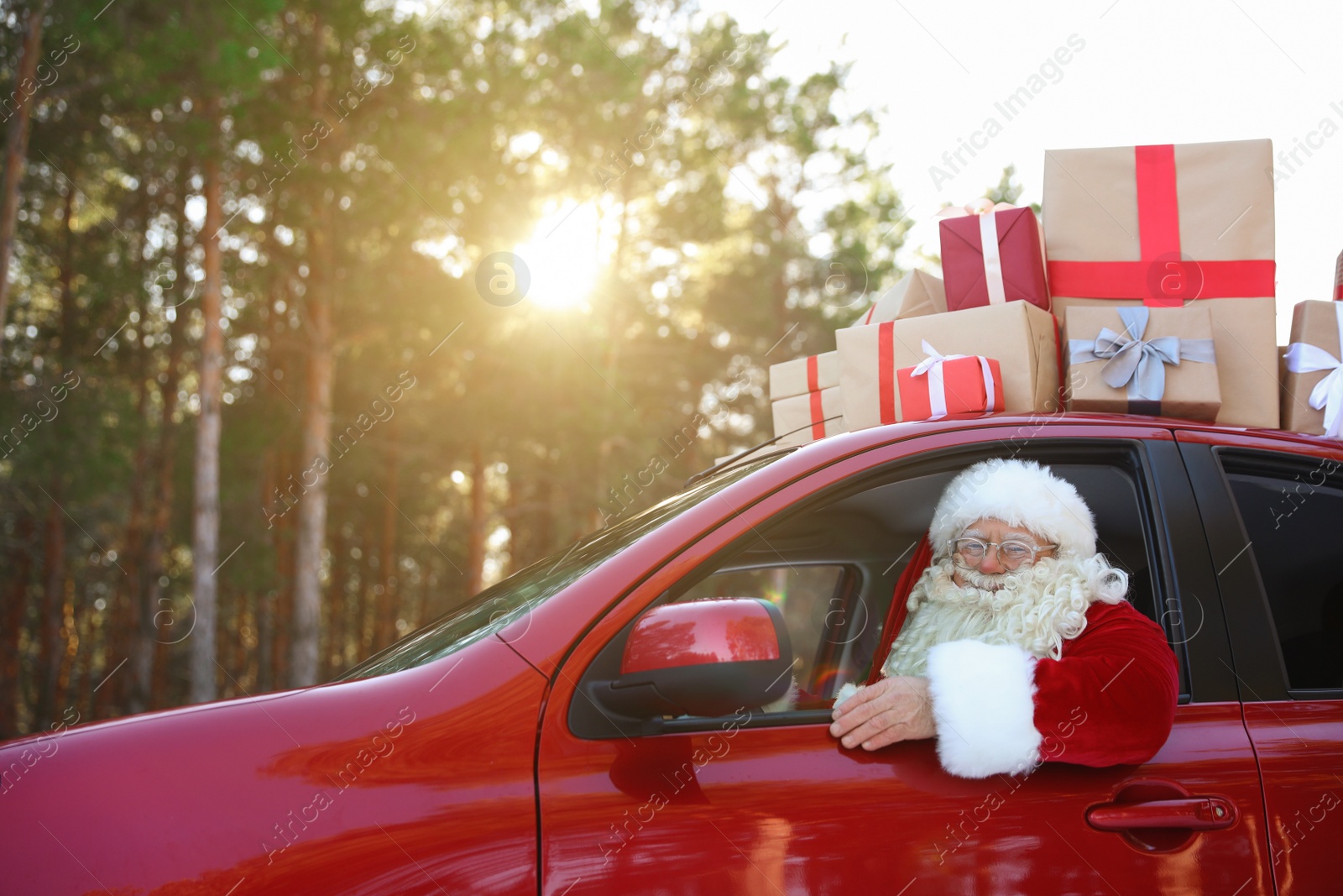 Photo of Authentic Santa Claus driving car with gift boxes, view from outside