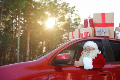 Authentic Santa Claus driving car with gift boxes, view from outside
