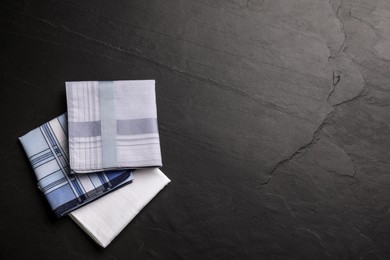 Different handkerchiefs folded on black table, flat lay. Space for text